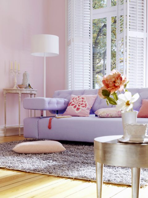 Soggiorno con pareti rosa pastello e divano lilla