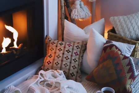 Un camino, cuscini, un tappeto, coperte e plaid per la casa invernale